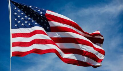 US Flag flying on blue sky background