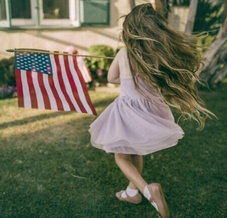 little girl dancing in the back yard with American flag