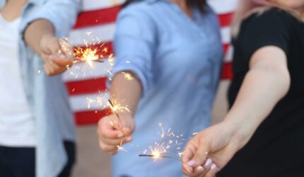 adults holding sparklers at July 4th celebration