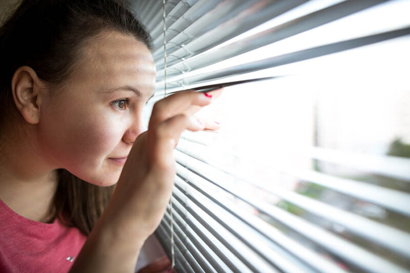 lady peeking out blinds to see buyers